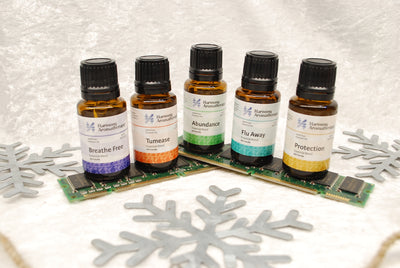 Five Essential Oils blends on table with snowflakes:  Breathe Free, Tumease, Abundance, Flu Away, Protection
